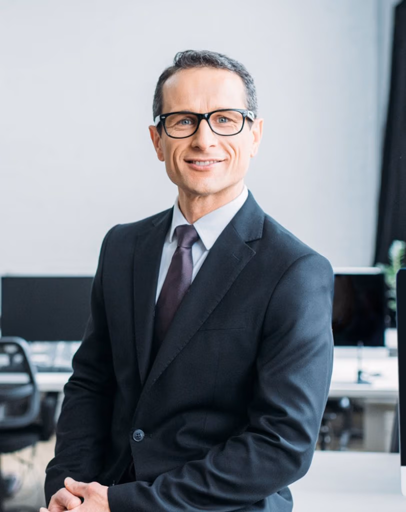 smiling businessman in eyeglasses sitting on table in office
